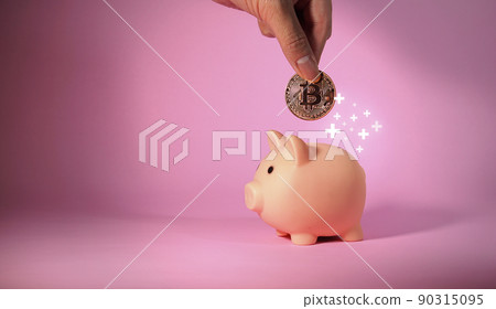 Hand of man drops metal bitcoin coin into piggy bank. Business and Finance. 90315095