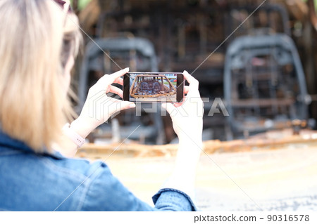 Female insurance broker or journalist photographs burned-out car after terrorist attack 90316578
