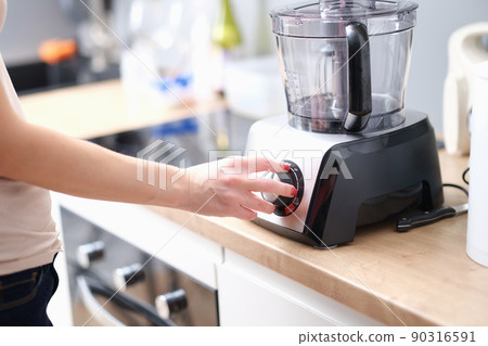 Woman turns on mixer for mixing products closeup 90316591