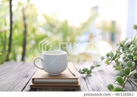 Small cup of coffee and notebooks and plant on wooden table 90316861