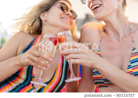 Two young adult girlfriends enjoy have fun celebrate happy moments drinking and cheers champagne wine glasses at ocean sea beach summer vacation. LGBT bisexual lifestyle life and travel concept Two young adult girlfriends enjoy have fun celebrate happy moments drinking and cheers champagne wine glasses at ocean sea beach summer vacation. LGBT bisexual lifestyle life and travel concept 90318787