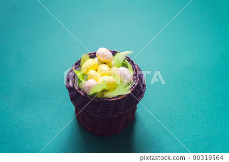 Easter composition with traditional decor. Small colorful eggs in wicker basket on soft background. Easter composition with traditional decor. Small colorful eggs in wicker basket on soft background. 90319564