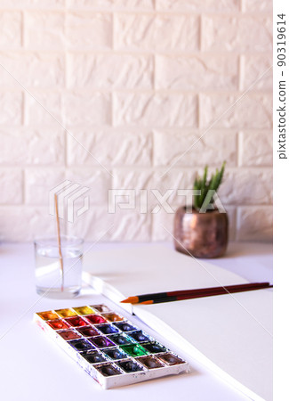 Watercolor paints, brushes and paper on white background. Flat lay, top view Watercolor paints, brushes and paper on white background. Flat lay, top view 90319614