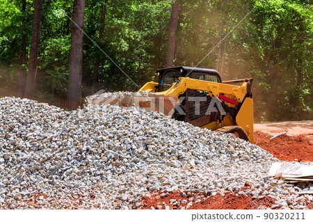 An excavator bucket rakes in crushed stone the excavator is picking up a full bucket 90320211