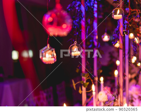 Candles in small glass circlular candle holders handled on strings. Beautiful decorations in purple electric light. Candles in small glass circlular candle holders handled on strings. Beautiful decorations in purple electric light. 90320365