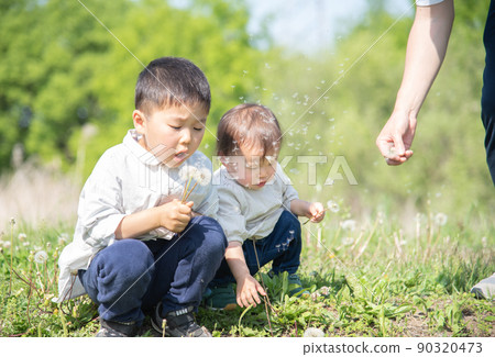 A 5-year-old boy and a 1-year-old girl blowing dandelion fluff A 5-year-old boy and a 1-year-old girl blowing dandelion fluff 90320473