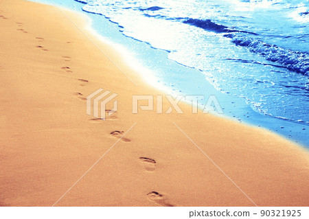 Walking on the beach, leaving footprints in the sand. Walking on the beach, leaving footprints in the sand. 90321925