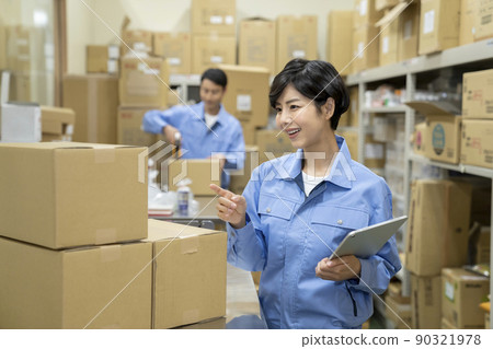 Image of a young woman working in a warehouse with a tablet for inventory management 90321978