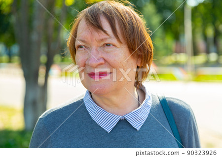 Portrait of positive mature woman standing outdoors Portrait of positive mature woman standing outdoors 90323926