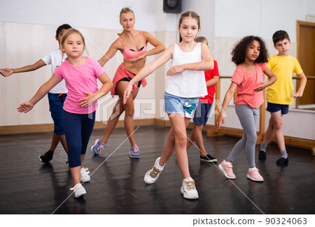Tween girl training vigorous dance during group class 90324063