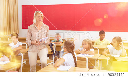 Teacher communicates freely with students in classroom at elementary school Teacher communicates freely with students in classroom at elementary school 90324111