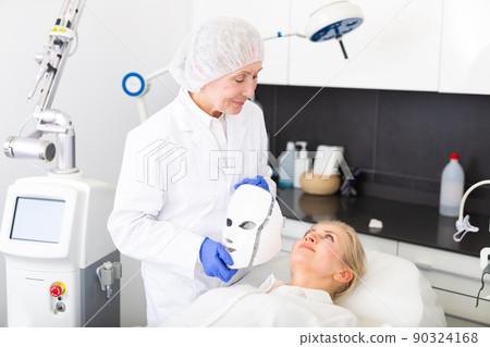 Cosmetologist using spectrum mask on young woman Cosmetologist using spectrum mask on young woman 90324168