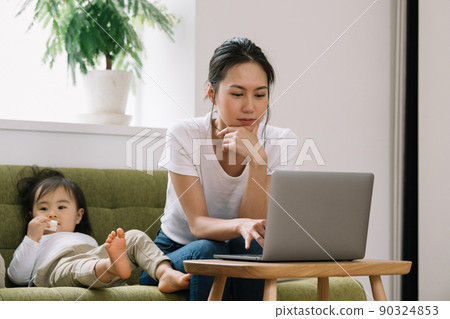 Image of a mother using a computer while baby-sittering Image of a mother using a computer while baby-sittering 90324853