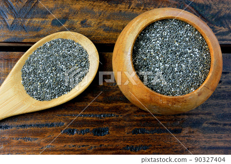 chia seeds in wooden bowl isolated on rustic table next to spoon 90327404