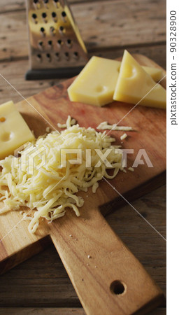 Vertical image of grated cheese and pieces of cheese with grater on wooden board Vertical image of grated cheese and pieces of cheese with grater on wooden board 90328900