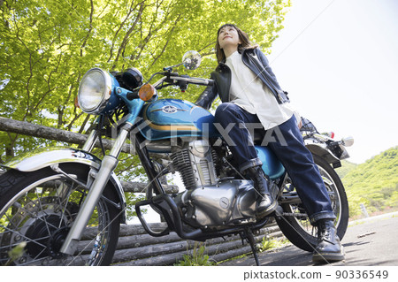 Bike girl image: A young woman leaning on a motorcycle 90336549