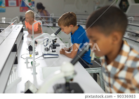 Multiracial elementary students looking in microscope during science practical in laboratory Multiracial elementary students looking in microscope during science practical in laboratory 90336983
