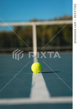 Surface level view of green ball on white line at empty court during sunny day 90337382