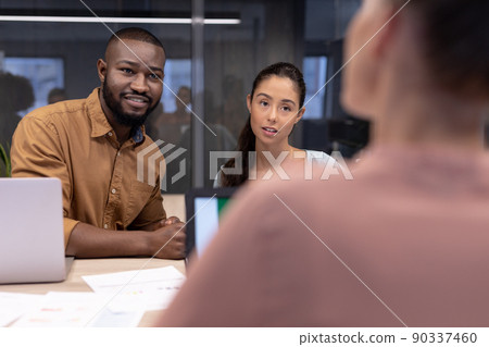 Young multiracial business colleagues looking at businesswoman discussing during meeting in office 90337460