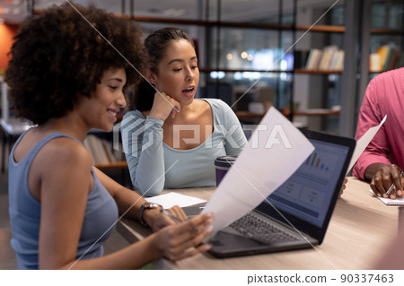 Biracial businesswomen discussing over laptop and document together during meeting at workplace Biracial businesswomen discussing over laptop and document together during meeting at workplace 90337463