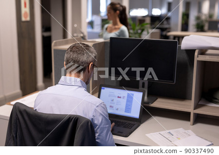 Rear view of mature caucasian businessman using laptop while working at modern workplace Rear view of mature caucasian businessman using laptop while working at modern workplace 90337490