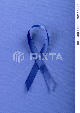 Close-up of blue stomach cancer awareness ribbon isolated against blue background, copy space 90338748