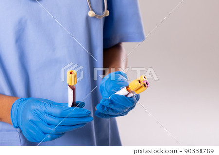 Midsection of african american mid adult female doctor wearing gloves holding test tubes, copy space Midsection of african american mid adult female doctor wearing gloves holding test tubes, copy space 90338789