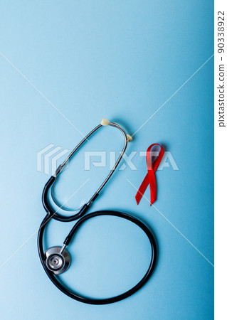 Directly above shot of red aids awareness ribbon and stethoscope against blue background, copy space Directly above shot of red aids awareness ribbon and stethoscope against blue background, copy space 90338922