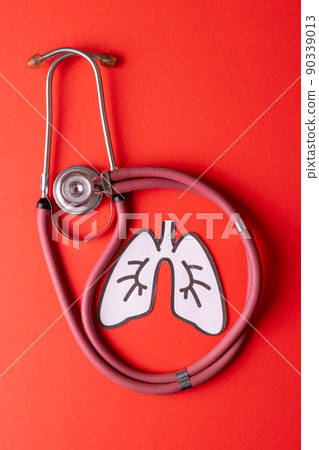 Directly above shot of white paper lungs with pink stethoscope over red background, copy space Directly above shot of white paper lungs with pink stethoscope over red background, copy space 90339013