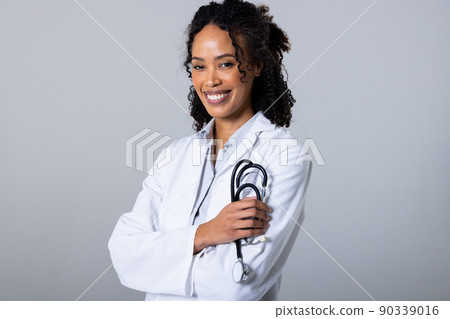Portrait of smiling african american mid adult woman holding stethoscope against white background Portrait of smiling african american mid adult woman holding stethoscope against white background 90339016