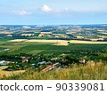 A view of the agricultural landscape of South Moravia around Mikulov. Fields and vineyard under blue summer sky. Suitable for tourist advertising. 90339081