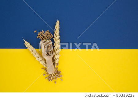 Wheat spilling from wooden scoop over blue yellow 90339222