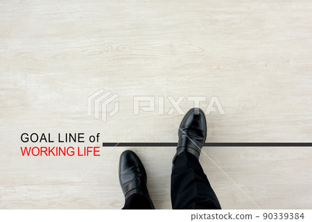 The feet of a businessman standing at the goal line of his working life 90339384