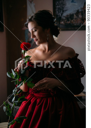 Beautiful woman in vintage 1800s early 1900s clothing red dress in old interior. Historical dresses, vintage outfits, beautiful retro dress reconstruction 90339423
