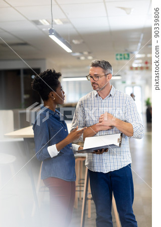 Young african american businesswoman discussing over file with caucasian businessman at workplace 90339806