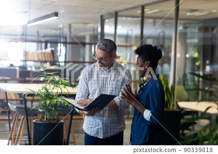 Caucasian businessman analyzing file while discussing with african american businesswoman at office Caucasian businessman analyzing file while discussing with african american businesswoman at office 90339818