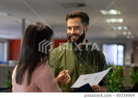Smiling caucasian businessman discussing over document with biracial businesswoman at workplace Smiling caucasian businessman discussing over document with biracial businesswoman at workplace 90339904