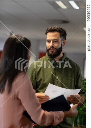 Confident caucasian businessman discussing over document with biracial businesswoman at workplace Confident caucasian businessman discussing over document with biracial businesswoman at workplace 90339912