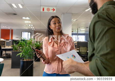 Surprised biracial businesswoman looking at caucasian businessman while discussing in workplace Surprised biracial businesswoman looking at caucasian businessman while discussing in workplace 90339939
