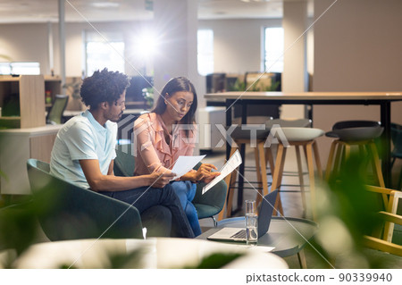 Confident female and male biracial colleagues discussing over document at modern workplace Confident female and male biracial colleagues discussing over document at modern workplace 90339940