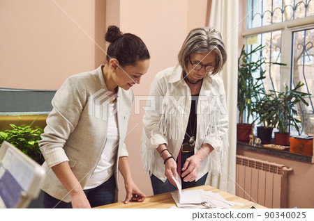 Senior fashion designer and tailor working with pattern in a fashion clothing design and tailoring atelier, creating new collection of clothes 90340025