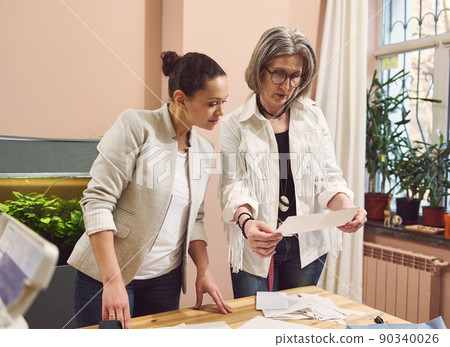 Two diverse female tailor fashion designers work with a sewing pattern to create new clothes in a fashion design and tailoring atelier. 90340026