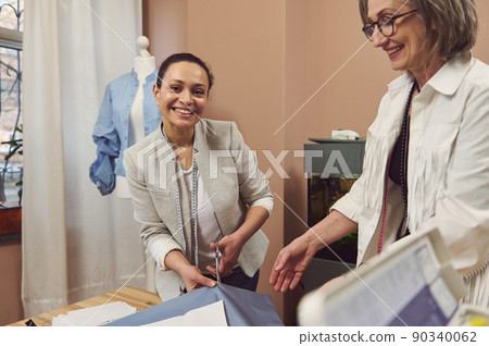 Hispanic pretty woman, tailor cuts a fabric while sewing clothes in a fashion design workshop. Fashion designer, seamstress, sewer, tailoring, creation on new garment concept 90340062