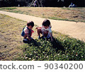 Old film photo Two sisters of a girl picking white clover 90340200