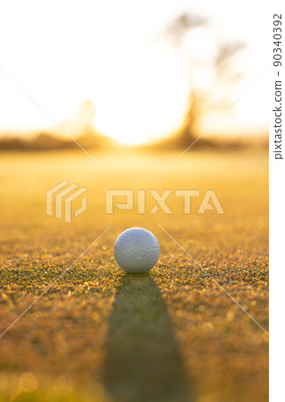 Close-up of golf ball on grassy landscape against clear sky during sunset, copy space 90340392