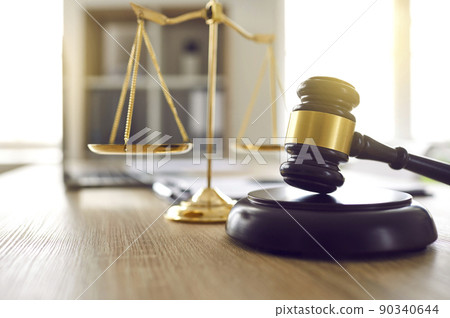 Brown judge's gavel on sound block and scales of justice on table in judge's office. 90340644