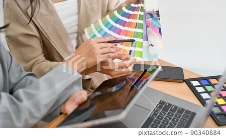 Two of a graphic designers are discussing and planning the web colour for their project together. 90340884