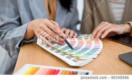 Two female graphic designers are reviewing the colour on the colour swatches palette Two female graphic designers are reviewing the colour on the colour swatches palette 90340886
