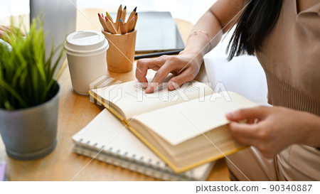 Relaxed woman reading a novel in her home workplace. cropped, close-up image Relaxed woman reading a novel in her home workplace. cropped, close-up image 90340887