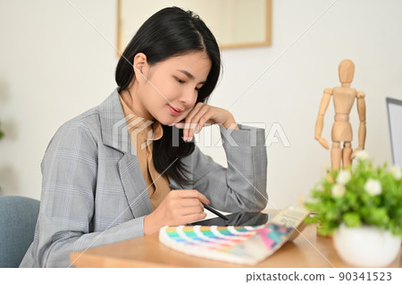 Beautiful Asian female graphic designer sits at her office desk, using digital tablet 90341523